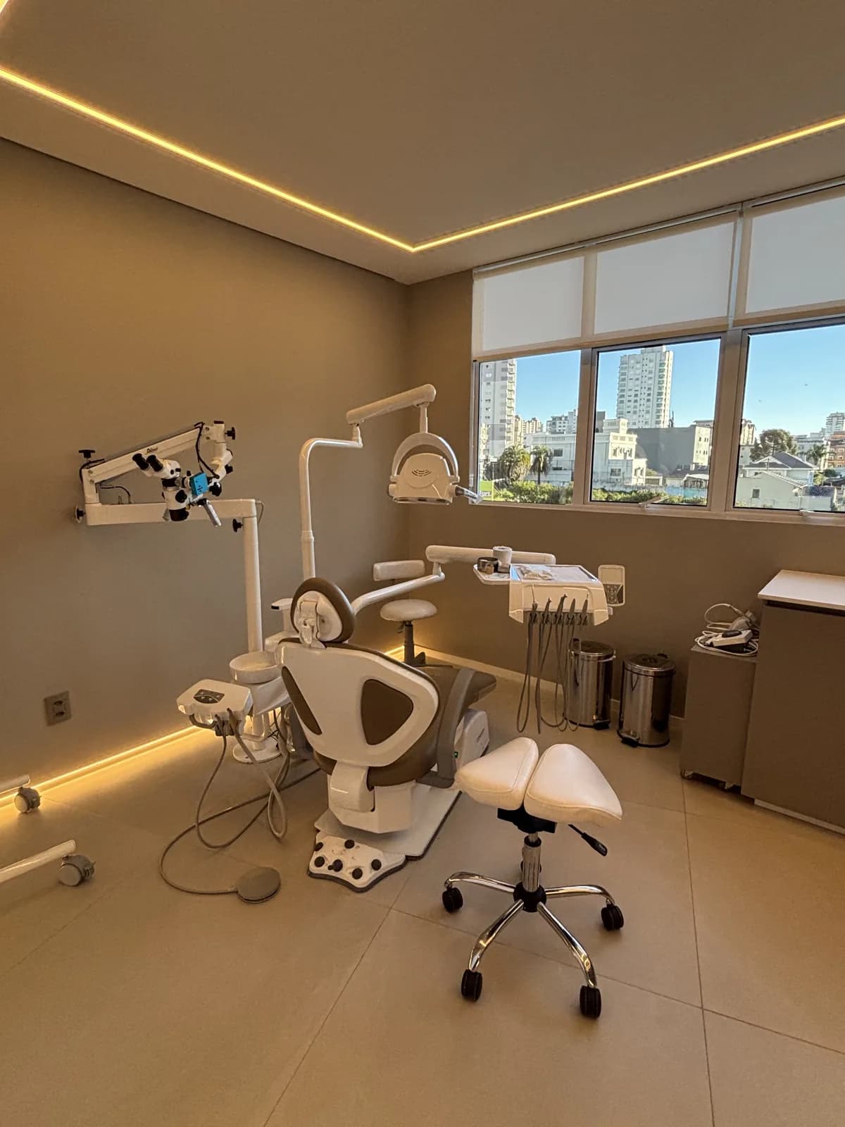 Consultório da LINEARE com cadeira odontológica e microscópio ao lado da janela.