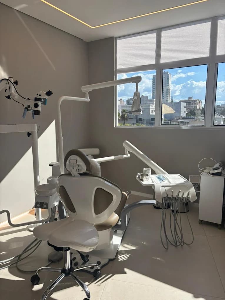 Consultório da LINEARE com cadeira odontológica, microscópio e janela.