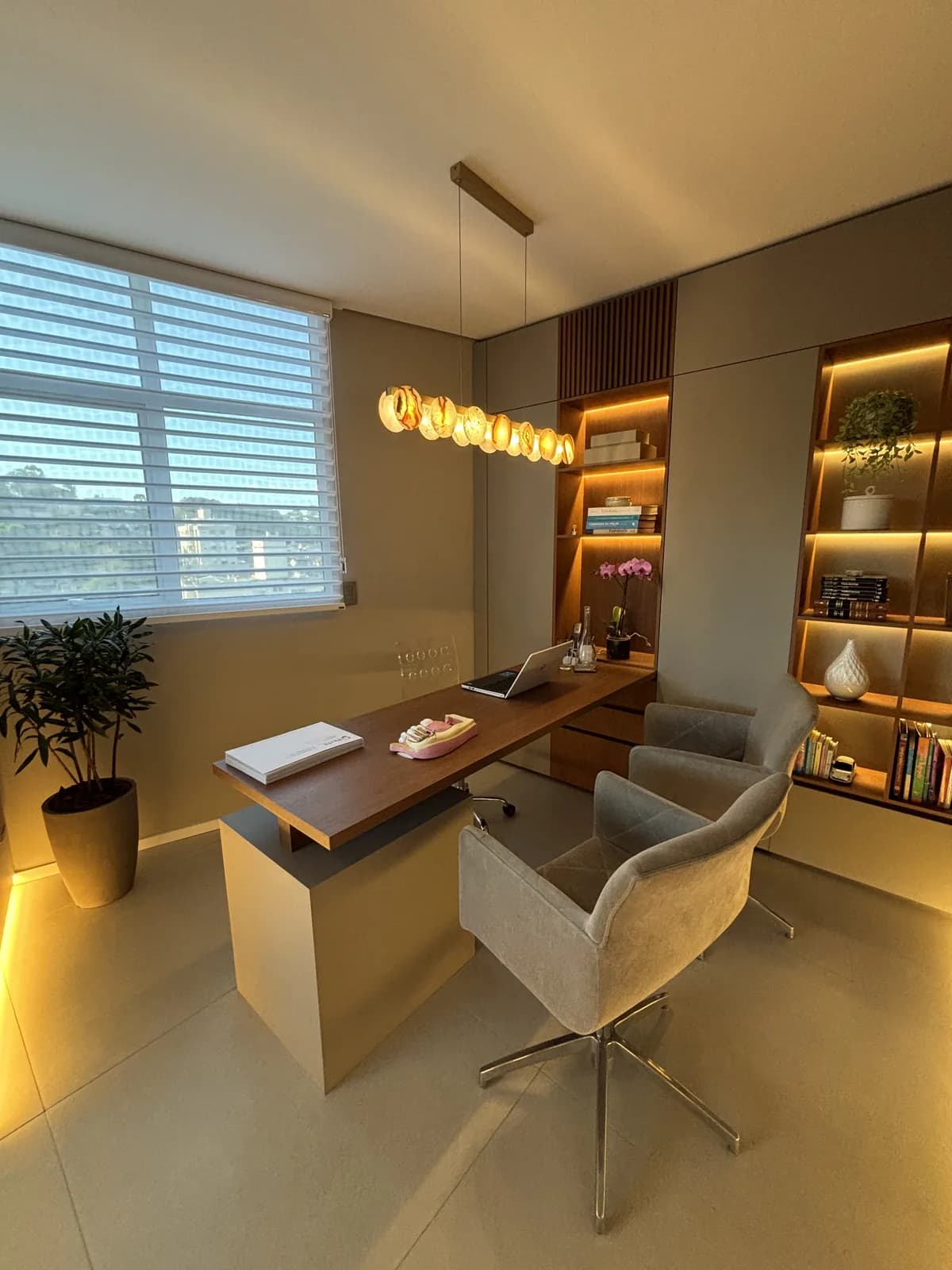 Sala da LINEARE com mesa de conversa, poltronas e estante iluminada.