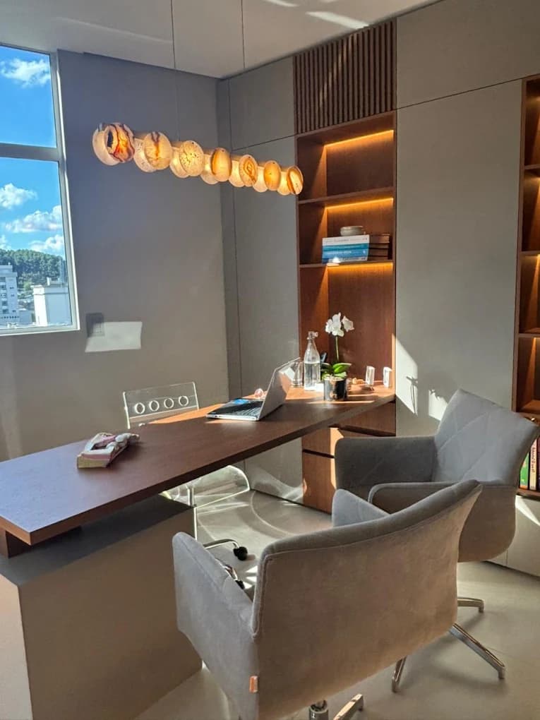 Sala da LINEARE com mesa, poltronas e estante iluminada.